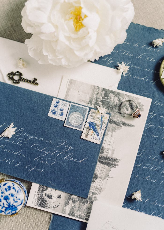 Charming flat lay of vintage stationery featuring elegant calligraphy, stamps, and a white peony flower.